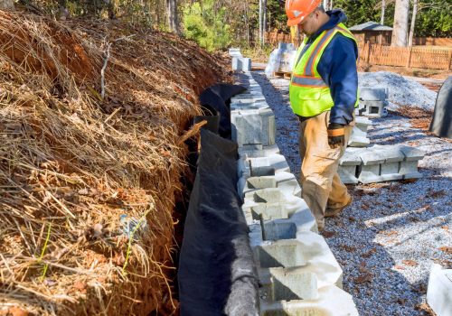 As new property is being developed construction worker is using cement blocks to construct retaining wall.